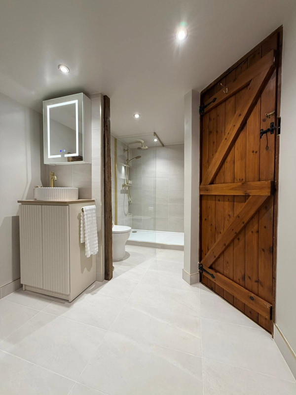Rustic bathroom with timber door, vanity, and shower view