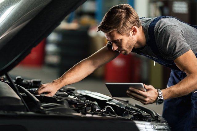 The Importance of Regular Car Battery Maintenance Car-mechanic-examining-engine-malfunction-while-using-touchpad-auto-repair-shop-min-Easy-Resize-com