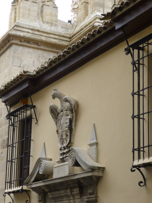 Decoration at the top of a door.  It is the side of an eagle holding a shield.  The design on the shield cannot quite be clearly seen.