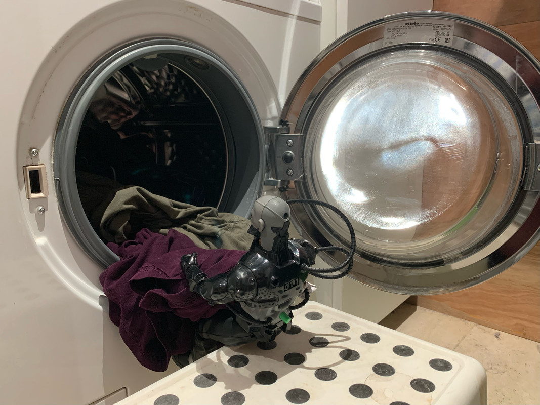 Black robot helping to Load in the dirty clothes into the washing machine. FC7-A4664-4-ECF-4-A21-823-F-5-AC7-F80-B55-D6