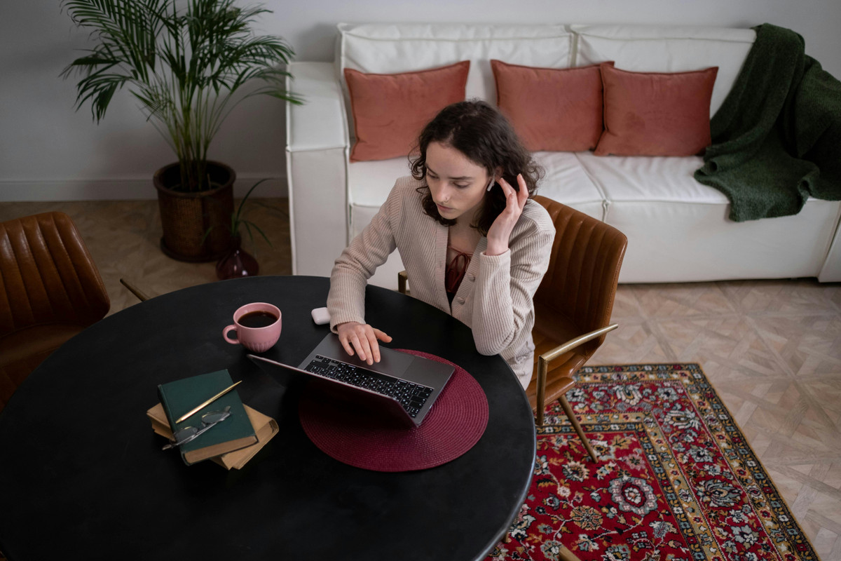 Hands typing rapidly on a laptop keyboard, a steaming mug of coffee sits beside it.