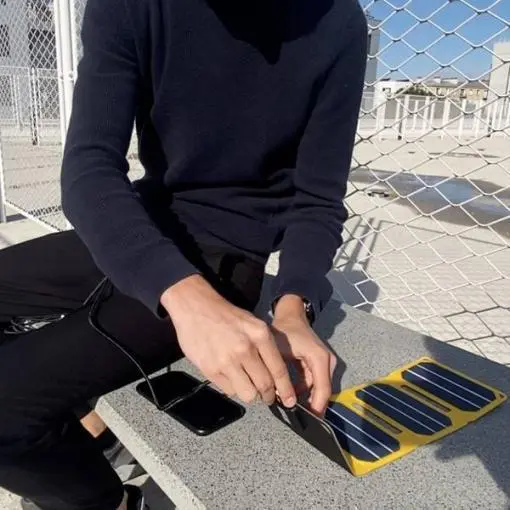 Un homme en train de deplier un mini panneau solaire pour portable