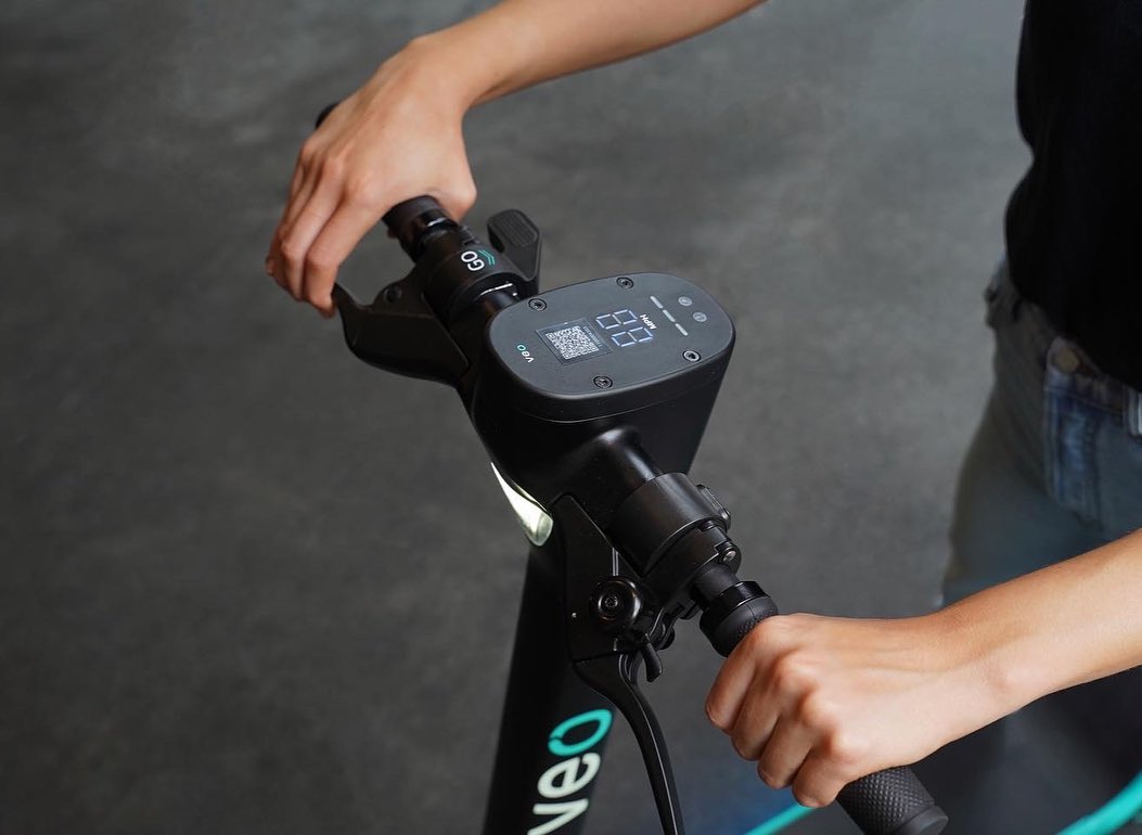 Close-up lifestyle product photography of hands holding electric scooter handlebars