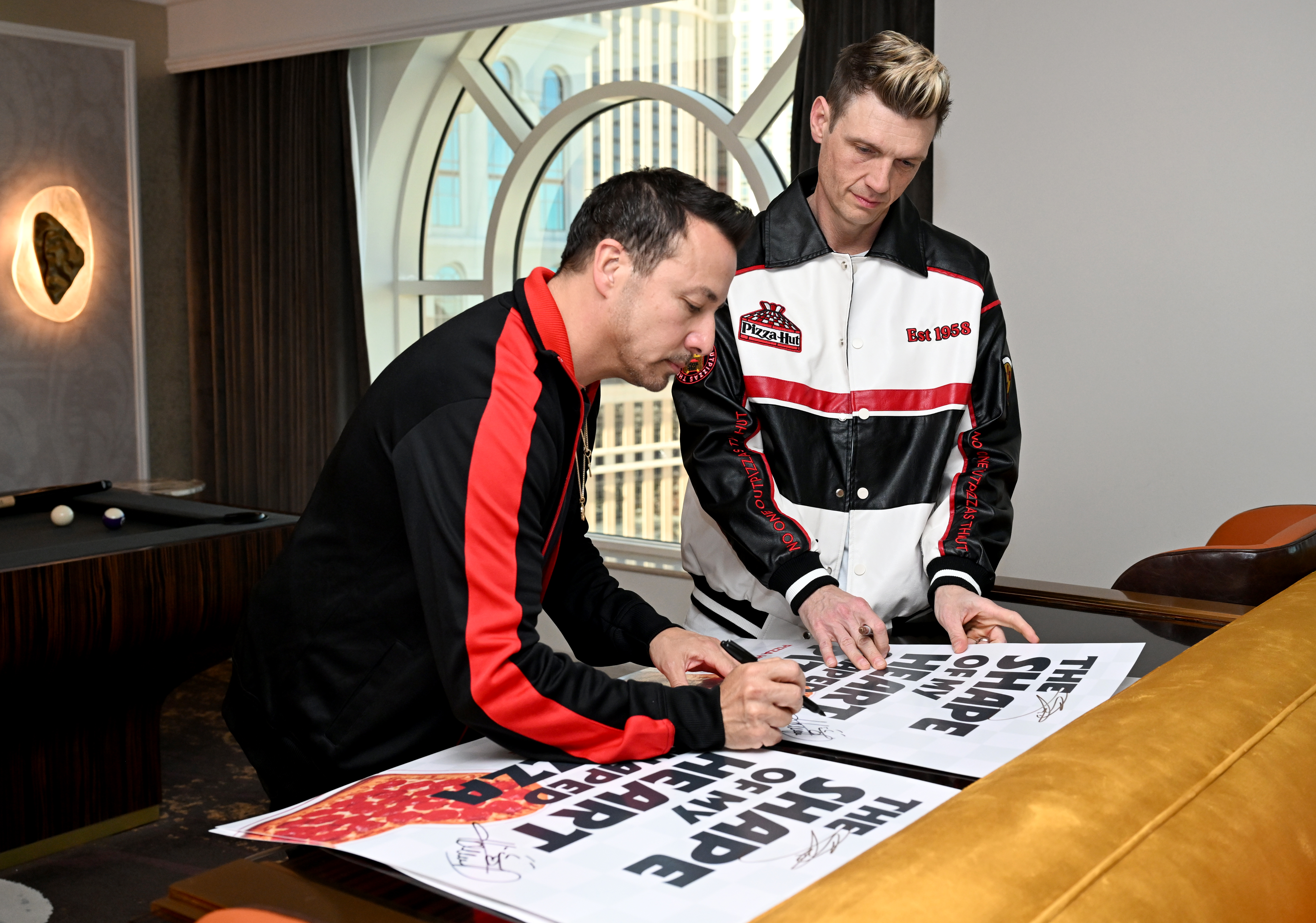 Howie Dorough and Nick Carter signing Shape of My Heart-Shaped Pizza posters
