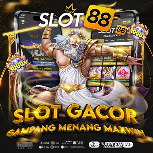 May include: A round stained glass window hanging featuring a green moth with a crescent moon and stars. The window is surrounded by a dark blue background with white flowers. The window is hanging in front of a window with a garden view.