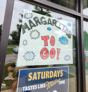 Hand-written storefront sign that reads Margaritas to-go