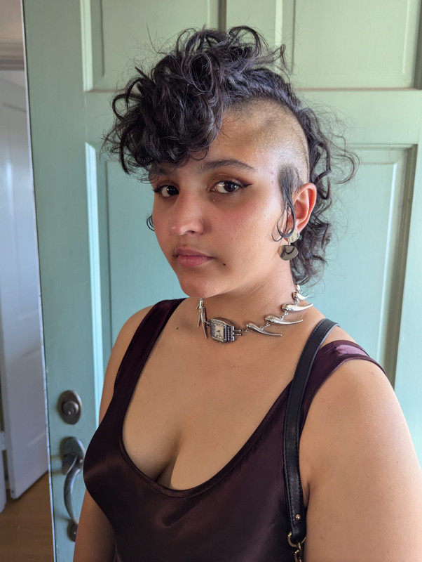a photo of myself in a burgundy slip dress, a silver choker with a watch piece in the center, silver earrings, and a styled mohawk