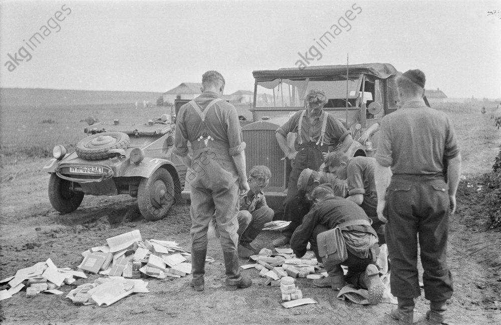 Wehrmachtssoldaten vor einem VW-Kübelwagen.