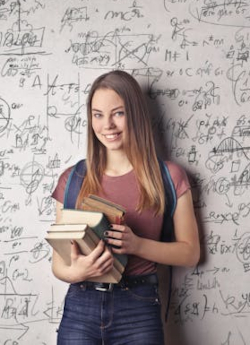 A student with books standing in a classroom