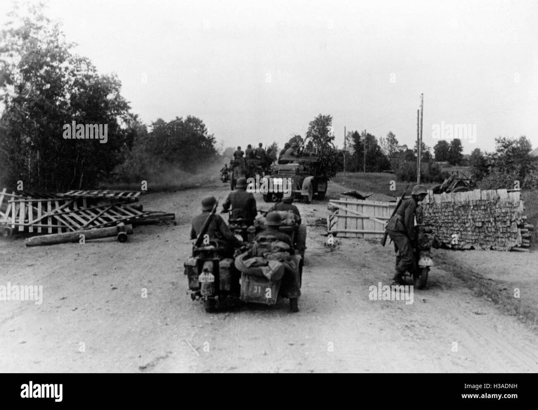 deutsche motorisierte truppen durchlaufen eine strassensperre an der ...
