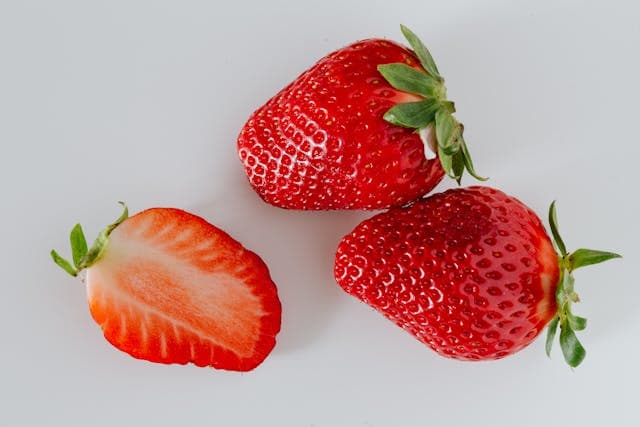 2 whole strawberries and one half-cut strawberry placed on a table