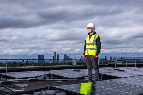 Homme sur toit d’un immeuble équipé de panneaux solaires avec nuage et sans soleil