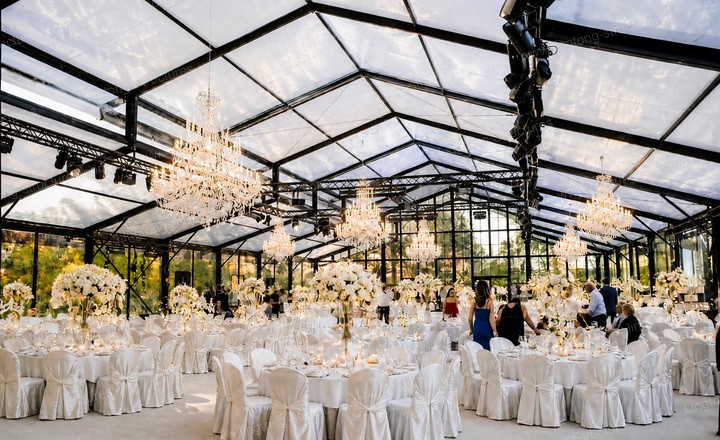 Glass atrium wedding tent at a lakeside venue with water reflections and natural lighting