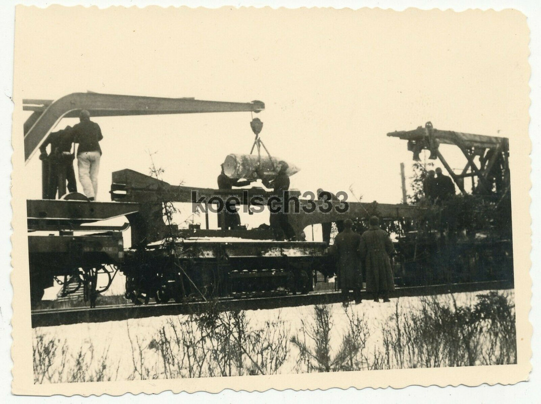 Foto Kanoniere laden mit einem Kran eine Granate für ein Eisenbahngeschütz auf