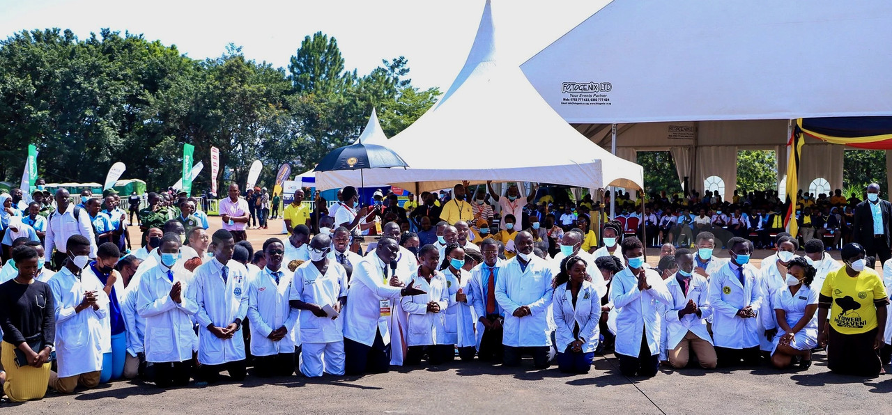 Dr. Samuel Oledo and colleagues kneeling before president Yoweri Kaguta Museveni