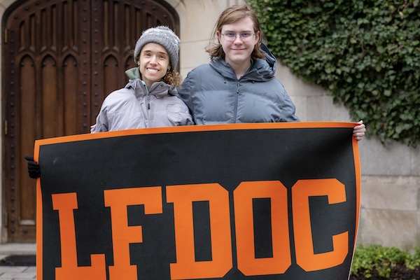 Two students smiling and standing holding LFDOC banner
