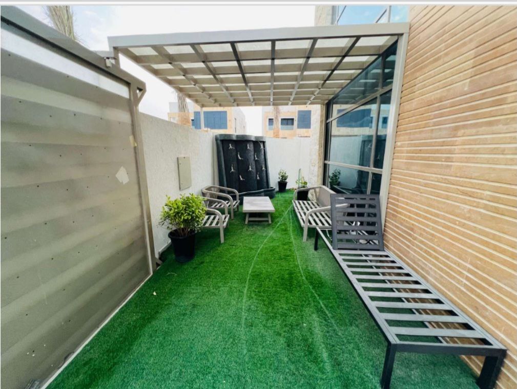 المجلس العشبي الخارجي في فيلا فاخرة بعجمان، يتميز بمساحة خضراء أنيقة توفر أجواء استرخاء وراحة في الهواء الطلق.