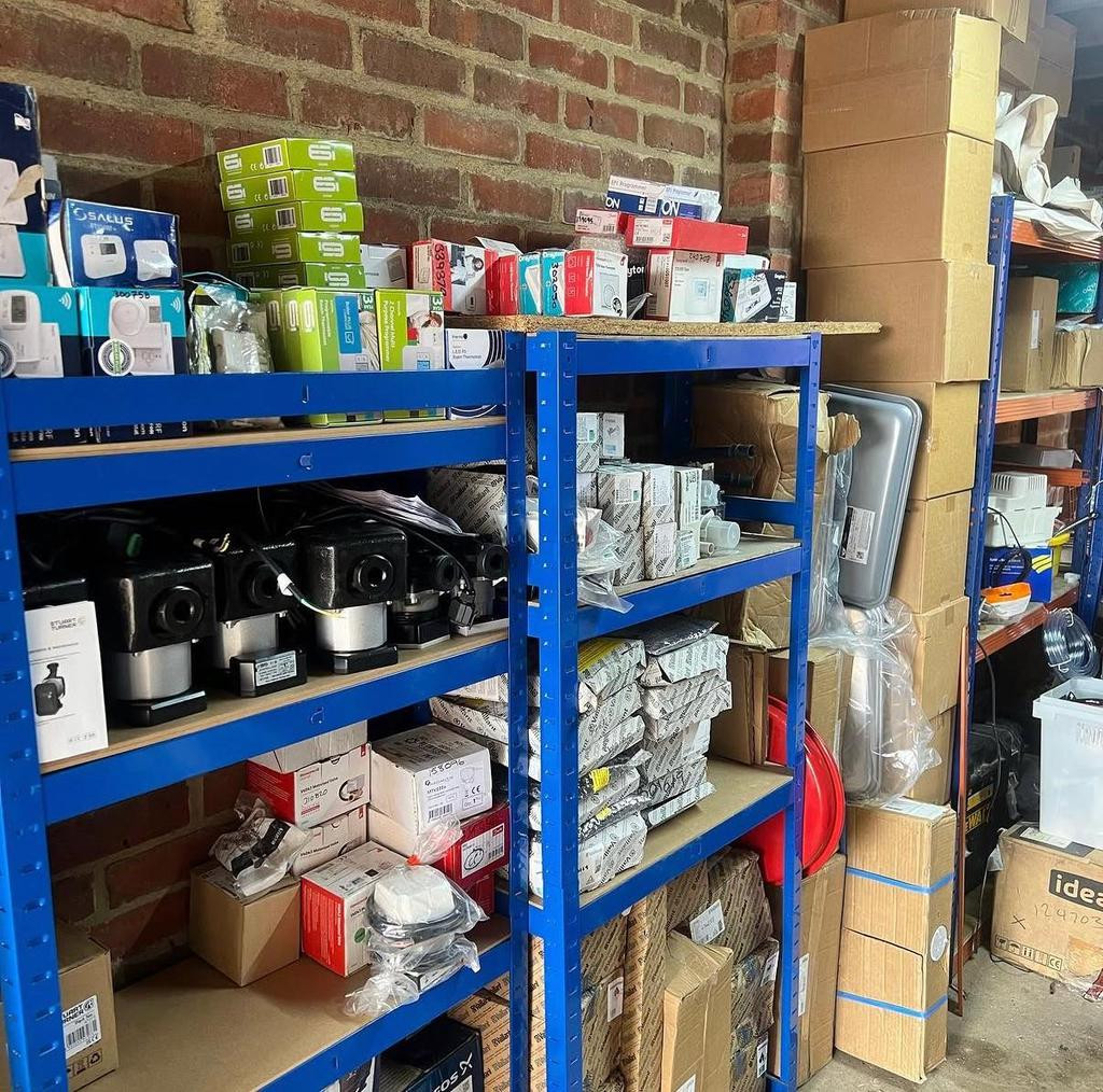 Shelves stacked with boxed boiler parts, pumps and controls in the KT Gas store