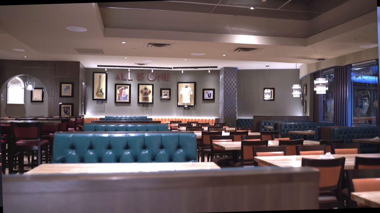 Hard Rock Cafe dining room with teal booths and framed music memorabilia under an All Is One sign