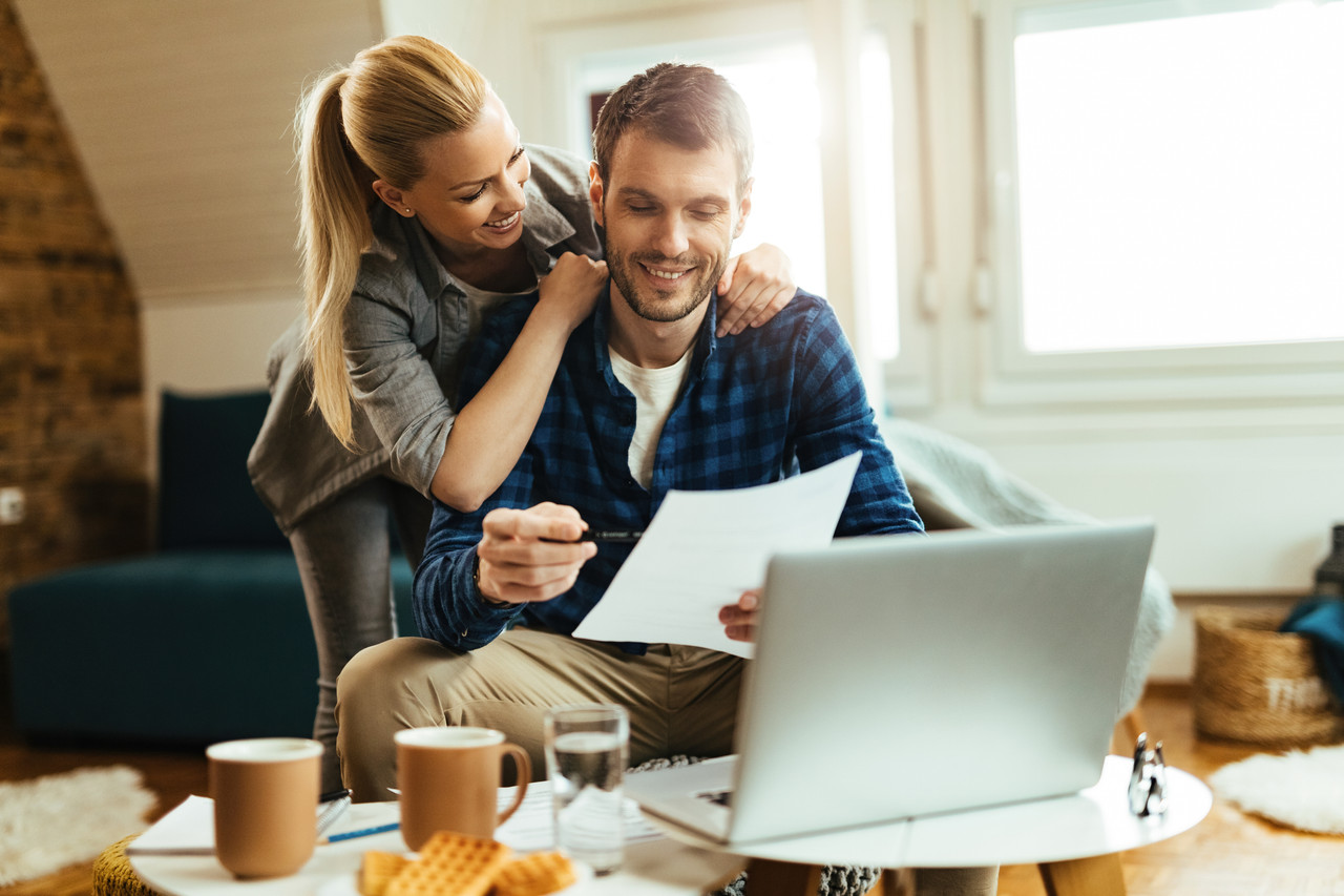 happy couple analyzing their home budget while paying bill computer