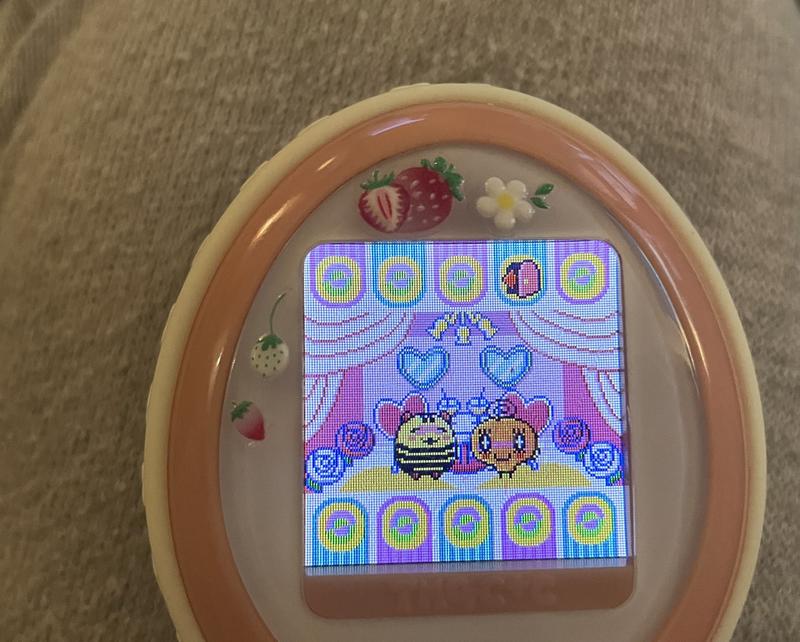 close up photograph of a tamagotchi plus color device. memetchi is standing with simasimatchi and they are both blushing