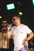 Ailton Souza cantando com banda e iluminação de palco