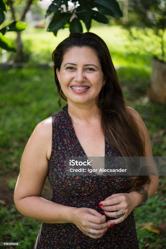 Retrato de uma mulher de 48 anos, Cláudia, com um sorriso satisfeito.