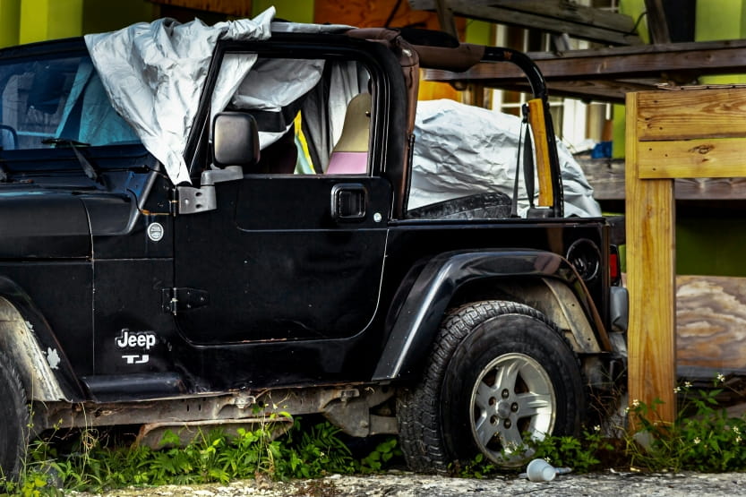 damaged Jeep with deployed airbags parked beside a building