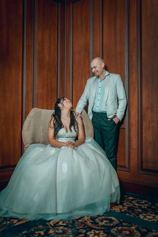 Esposos viéndose en salón elegante, ella sentada, él a su lado