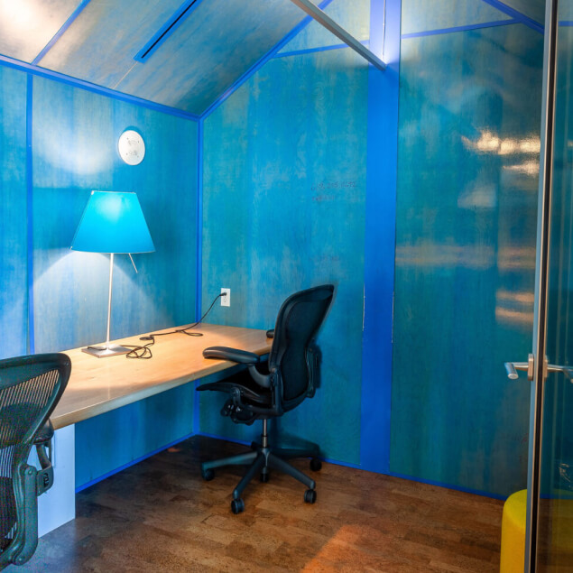 Blue-walled room with desk, lights, and glass enclosure