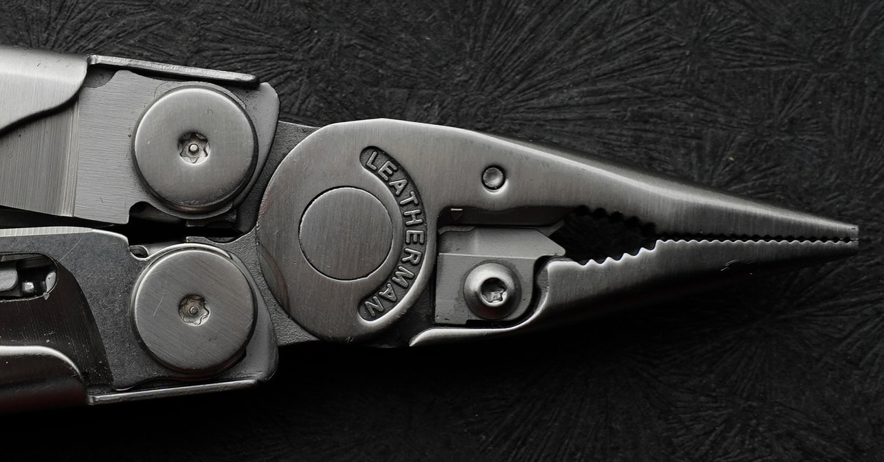 Close-up product photography of a metal multi-tool on a dark textured background
