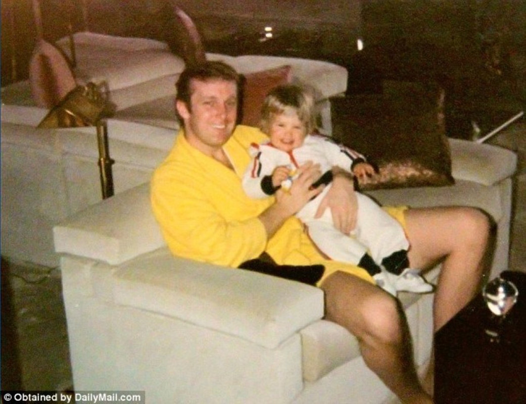 Donald Trump in yellow bathrobe holding his one of the sons.