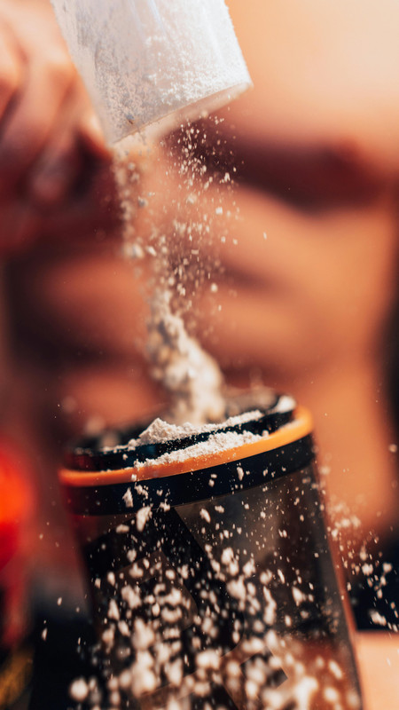 Person mixing creatine powder into water after a workout