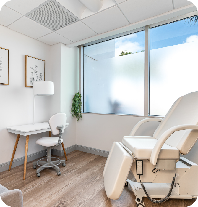Cozy office space featuring a comfortable reclining chair and a small desk with a chair. The room has natural light from a large window with frosted glass for privacy.