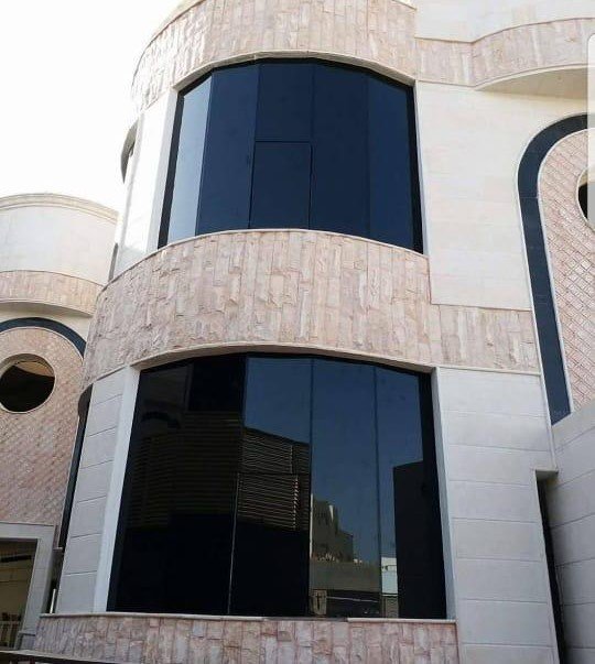 واجهة زجاجية داكنة منحنية على زاوية مبنى خارجي