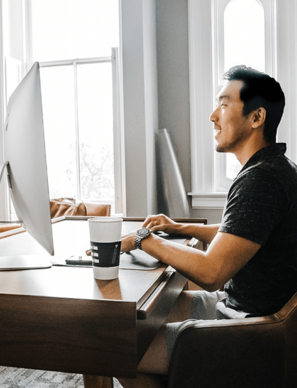 Man focused on a computer monitor at a desk in a bright office.