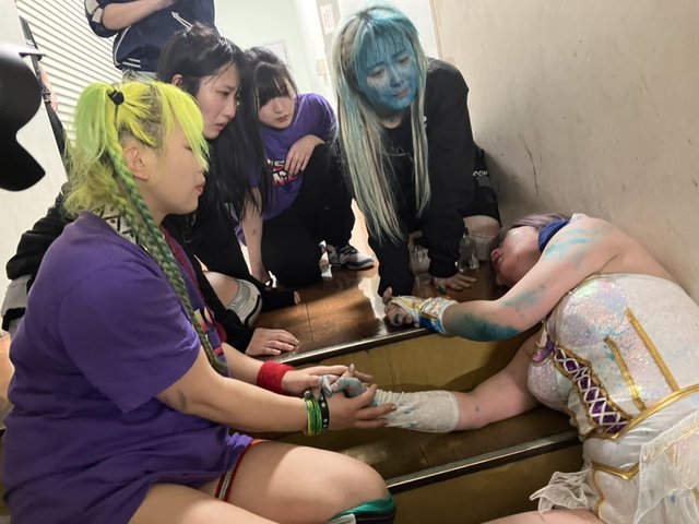 Photo from Tokyo Sports of Tam lying down on the staircase while her Cosmic Angels comrades are near her.