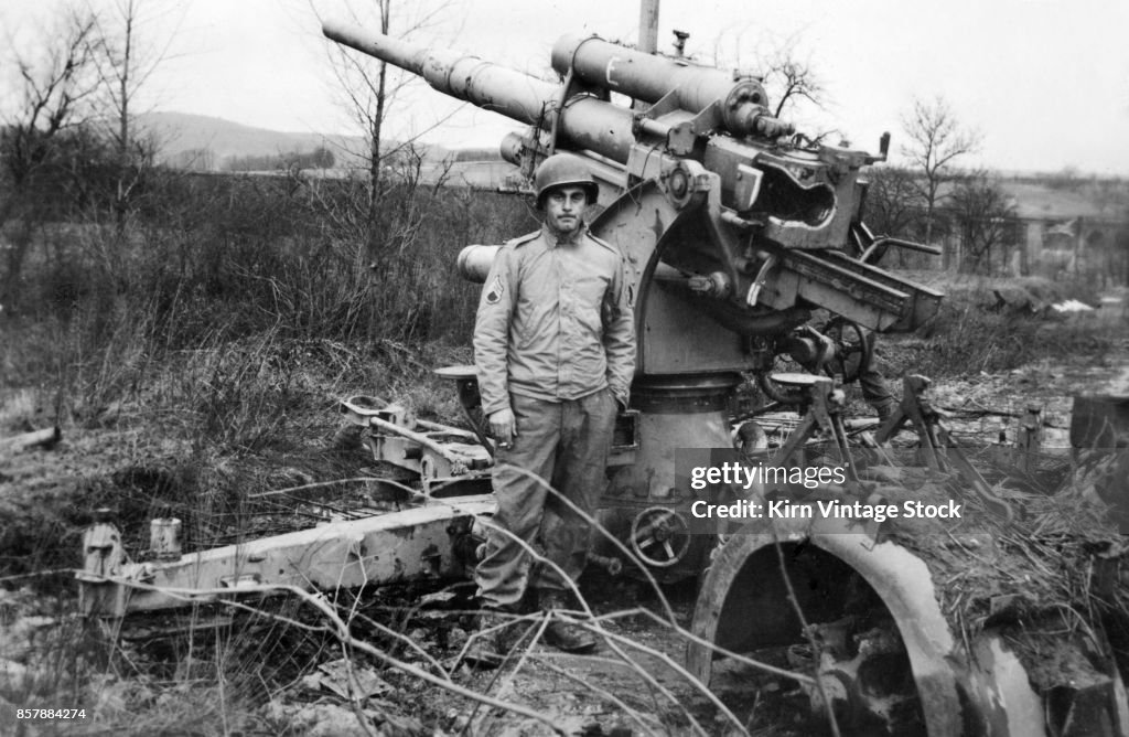 A US Army soldier poses in front of captured German artillery battery during the liberation of Franc