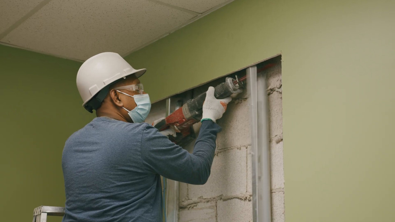 Worker cutting a new opening in a block wall during the office renovation