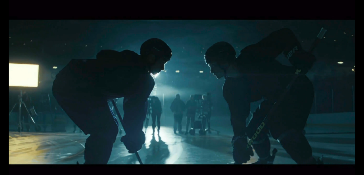 shane and ilya crouched for a face-off while filming a commercial. they are lit from behind so they're mostly in silhouette.