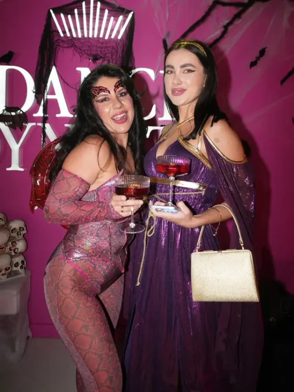 Two guests in costume raising cocktails