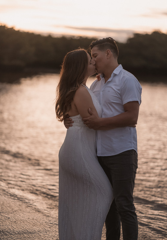 Esposos abrazados y besándose al atardecer en la playa