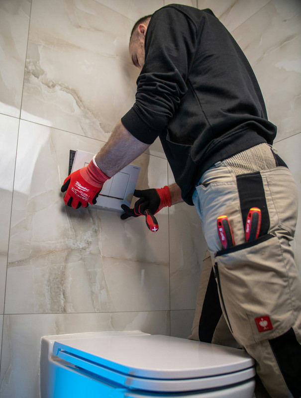 Plumber repairing a pipe under sink