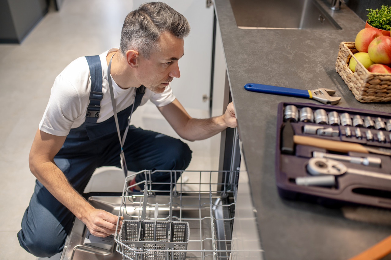 dishwasher repair top view middleaged man crouching near open dishwasher