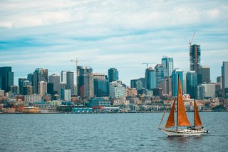 A sailboat on the water with the Oregon city skyline in the background