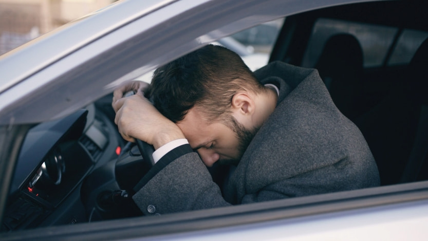 A frustrated man in a suit sitting in a car
