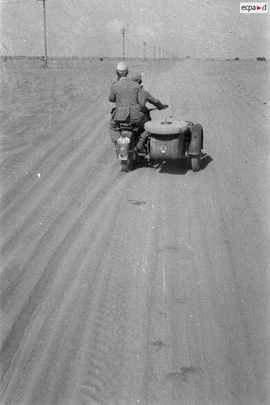Un side-car BMW R75 roule dans le désert, le long de la piste baptisée du télégraphe.1942