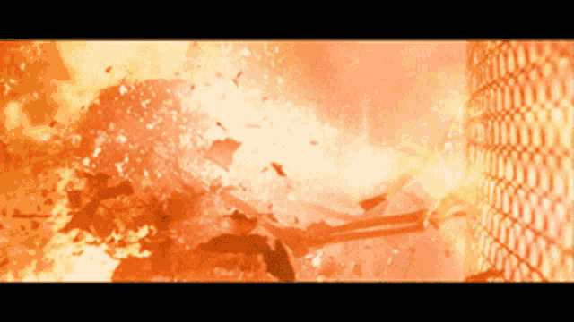 A GIF OF A SKELETON PULLING BACK ON A CHAIN LINK FENCE AS IT EXPLODES.