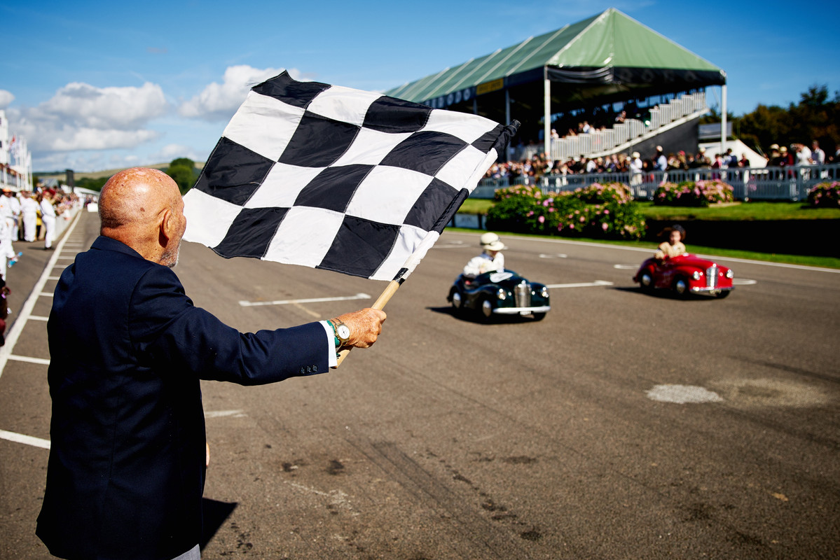 SirStirlingMosswavesthechequeredflagatGoodwoodRevival'sSettringtonCup,2016.(c)DominicJames