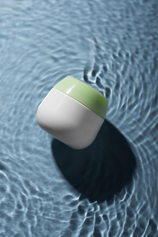 Cosmetic bottle on glossy surface with reflection